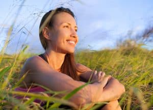 Woman sitting and smiling in a grass field