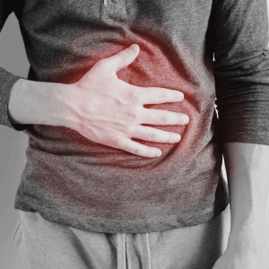 A person wearing a long-sleeve shirt is clutching their stomach with one hand. The area under their hand is highlighted in red, suggesting pain or discomfort. The rest of the image is in grayscale, evoking the need for Pain Management Long Island expertise.